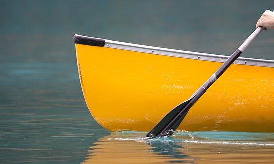 An energetic stroke sends a canoe gently down the stream.