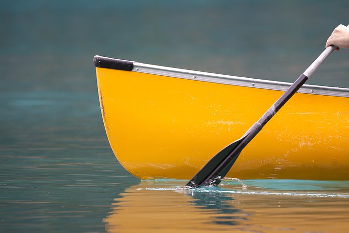 An energetic stroke sends a canoe gently down the stream.